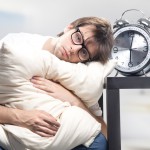 Sad man holding pillow and the clock